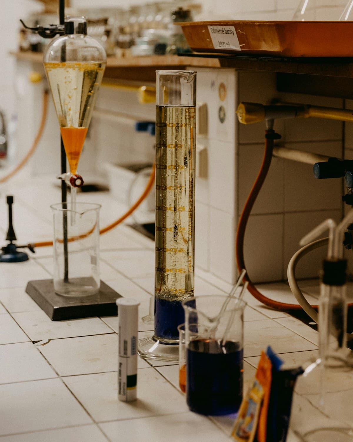 Montaje de laboratorio con una columna graduada, embudo de decantación, recipientes con líquidos y mangueras sobre una mesada.