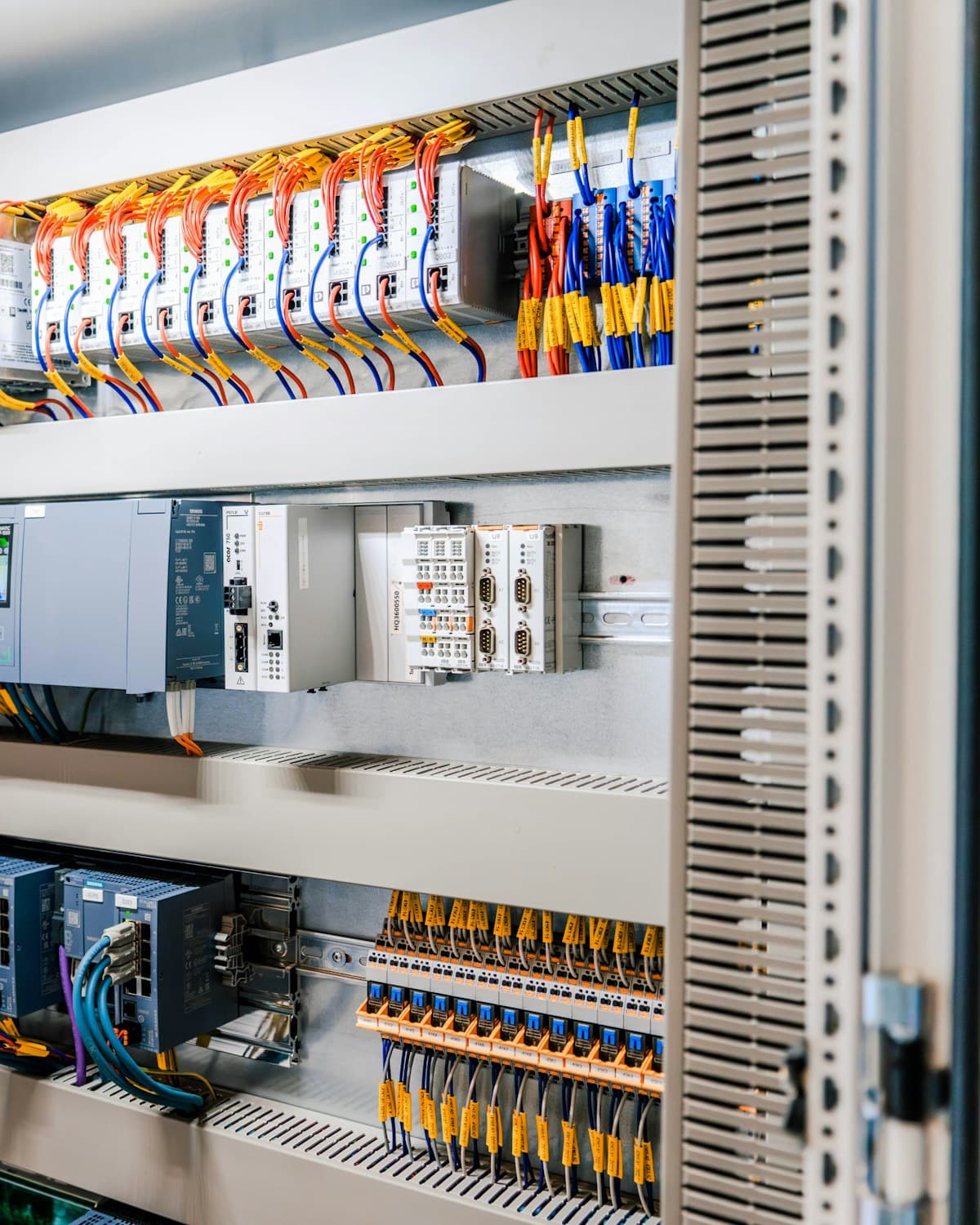 Tablero eléctrico industrial abierto con módulos de control, cables de colores y canaletas organizadas.