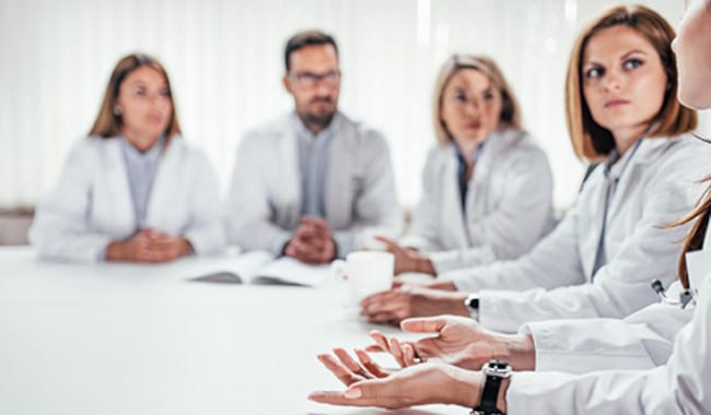Grupo de personas con guardapolvos reunido alrededor de una mesa