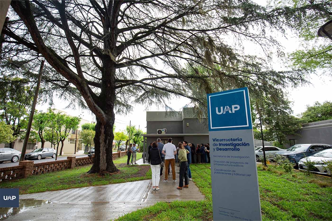 Sendero arbolado frente a un edificio de la UAP con personas caminando