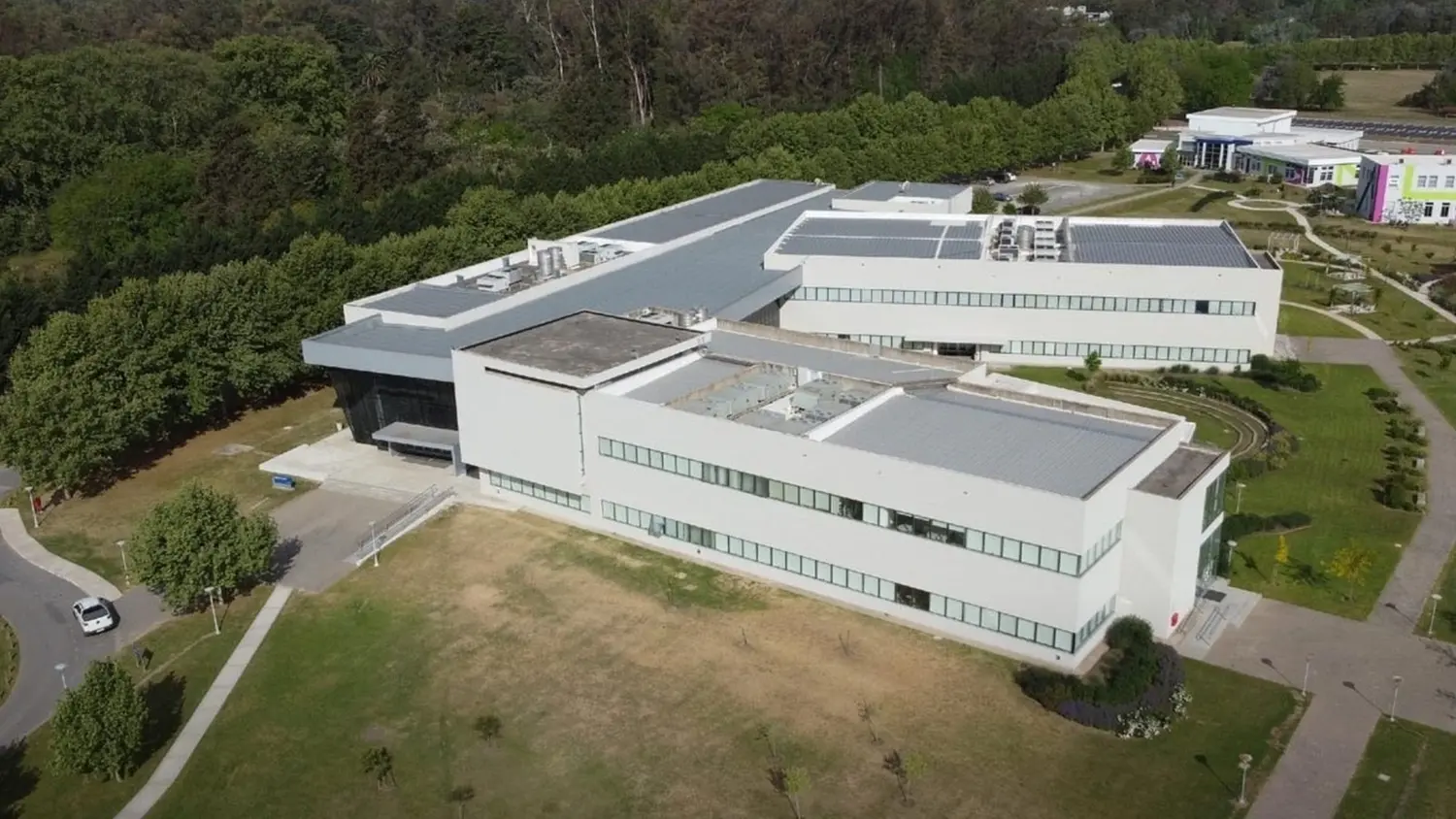Vista aérea de un edificio universitario rodeado de áreas verdes y senderos