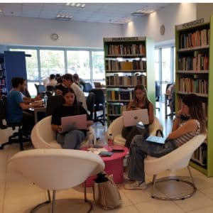 Estudiantes sentados en una biblioteca usando computadoras portátiles
