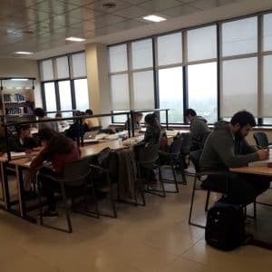 Personas estudiando en mesas de una sala de biblioteca
