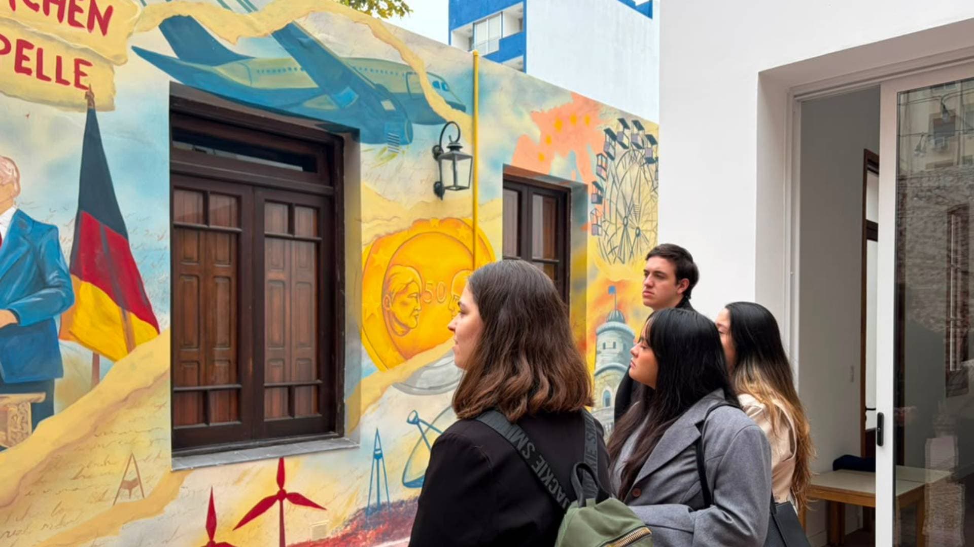 Estudiantes observan un mural en un pasillo interior de la universidad.