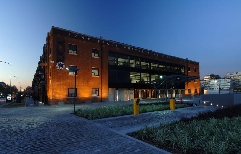 Edificio de ladrillo de la Universidad Católica Argentina, iluminado al atardecer, con acceso peatonal y áreas parquizadas.