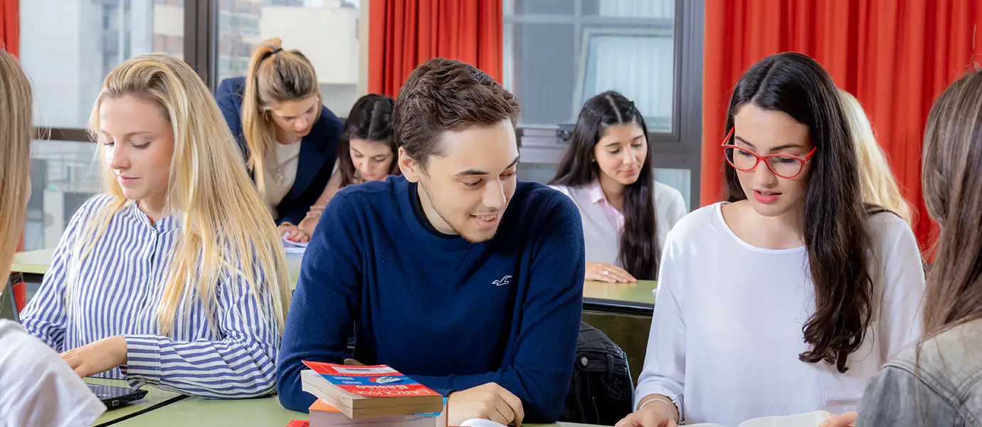 Estudiantes trabajando con apuntes y libros en un aula