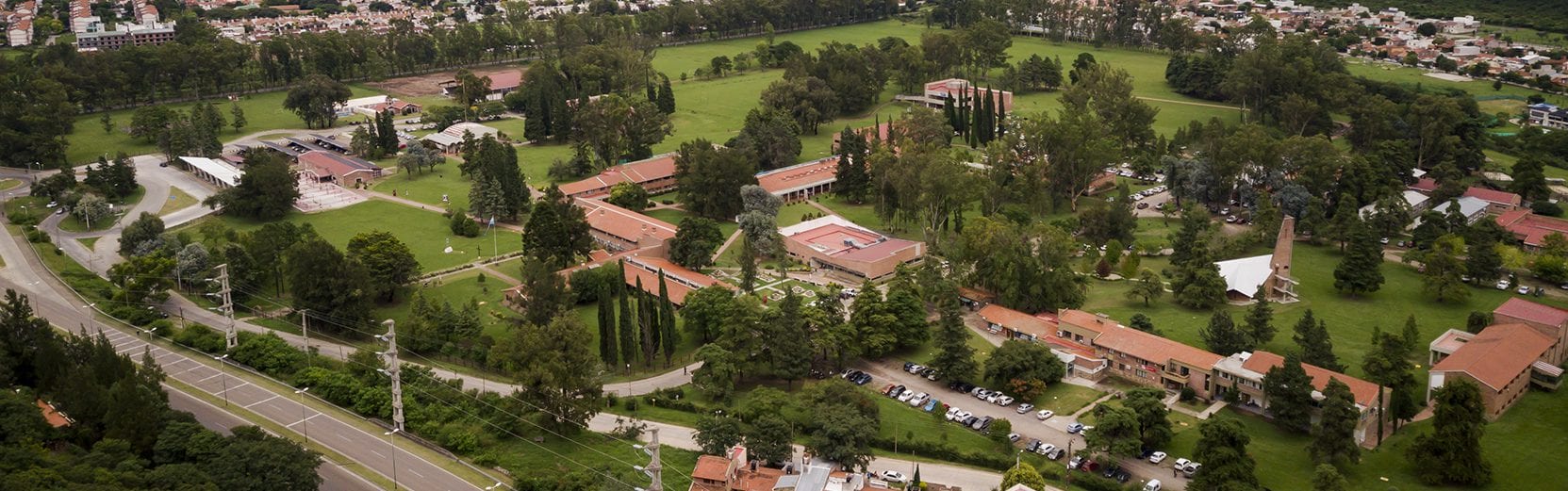 Vista aérea de edificios bajos, áreas verdes y caminos del campus universitario.