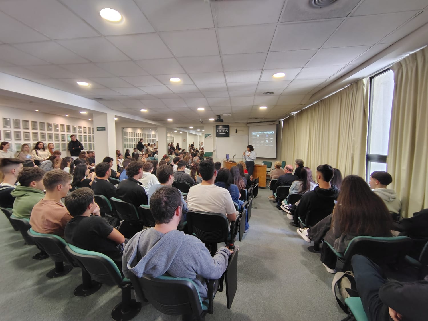 Vista amplia de un aula auditorio con estudiantes sentados durante una presentación.