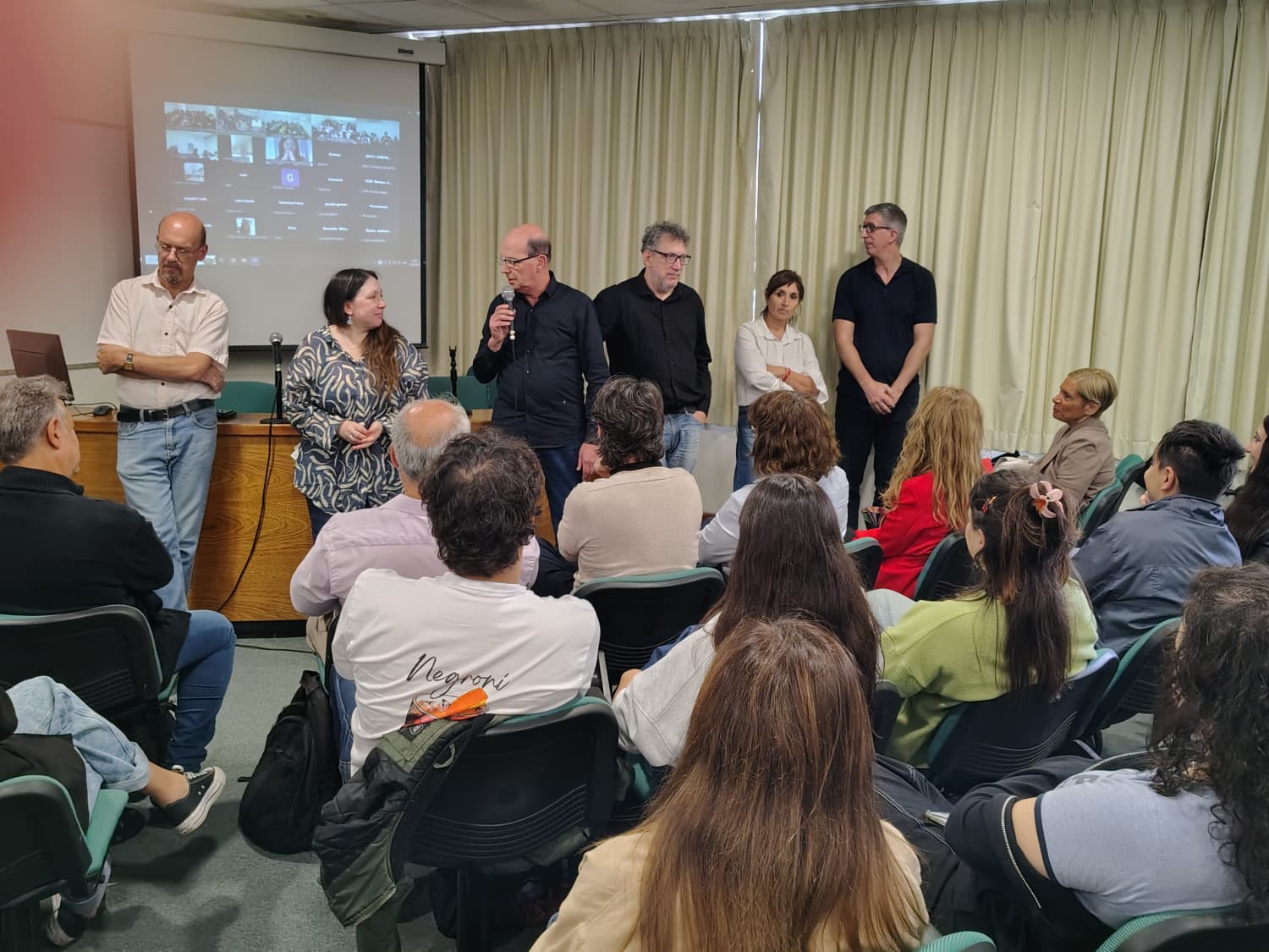 Asistentes sentados frente a un grupo de docentes durante una presentación en aula.