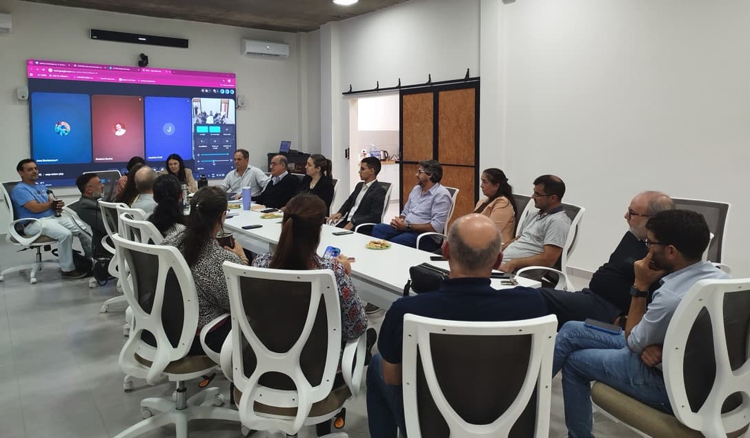 Grupo de personas reunido en una sala equipada con pantalla de videoconferencia.
