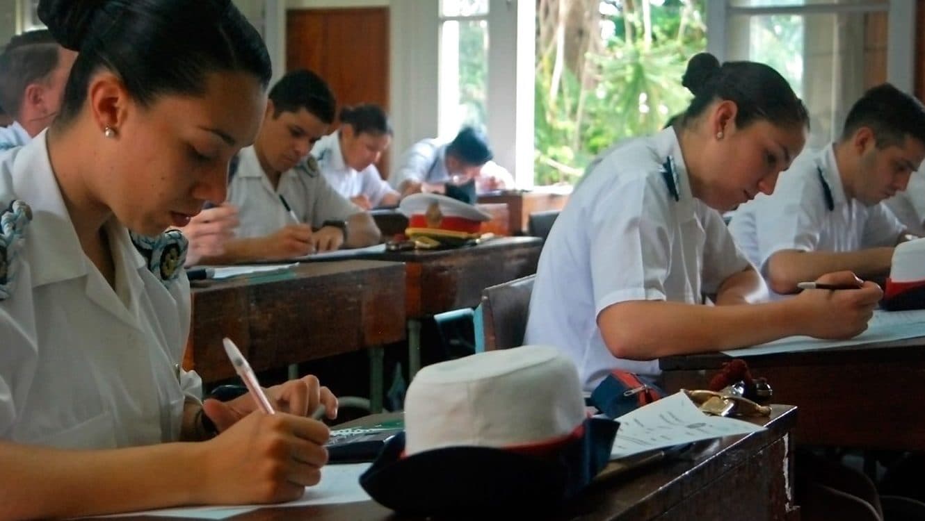 Estudiantes sentados en un aula, tomando apuntes durante una clase.