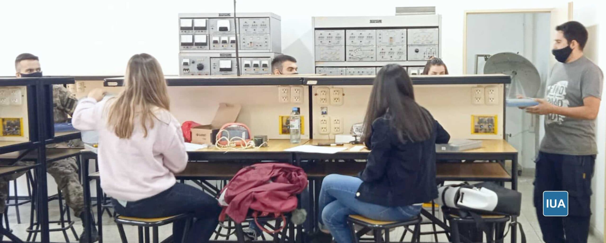 Estudiantes realizan prácticas en un laboratorio con equipos electrónicos.