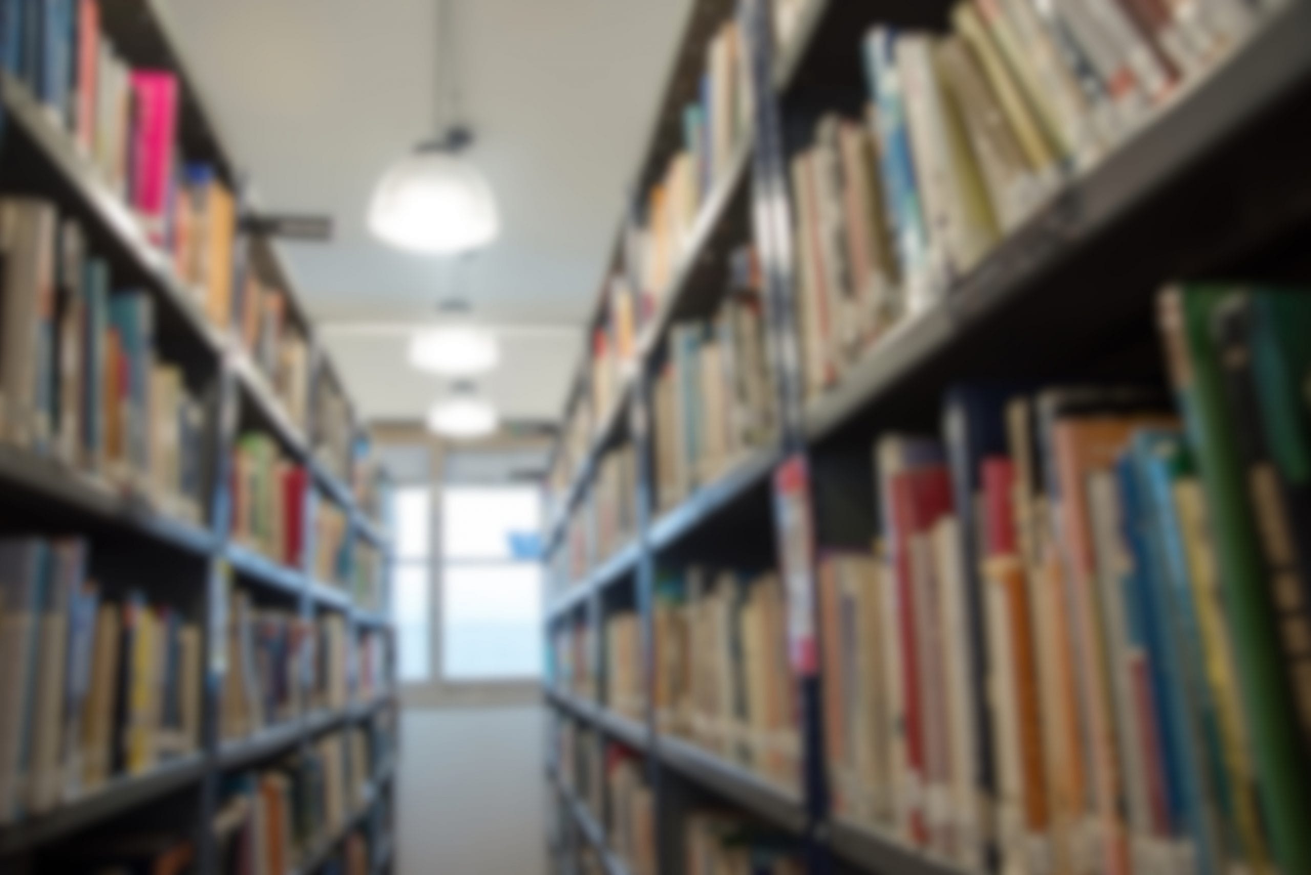 Pasillo de biblioteca con estanterías de libros a ambos lados.