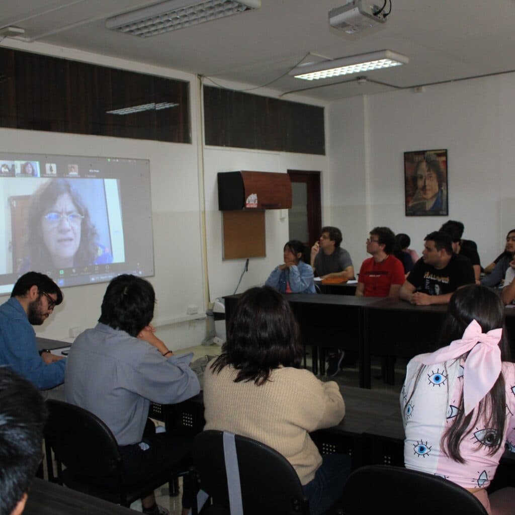 Estudiantes sentados en un aula durante una clase con proyección en pantalla.