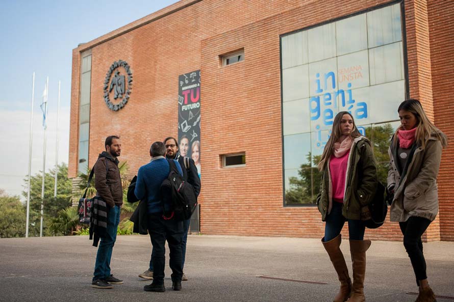 Estudiantes reunidos frente a un edificio de ladrillo de la UNSTA.