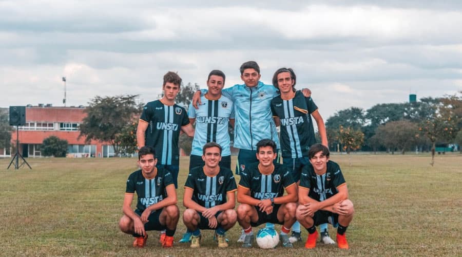 Equipo de estudiantes con indumentaria de la UNSTA en una cancha.