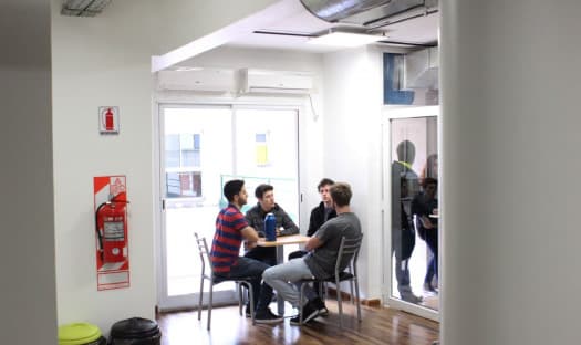 Estudiantes conversando alrededor de una mesa en un área interior