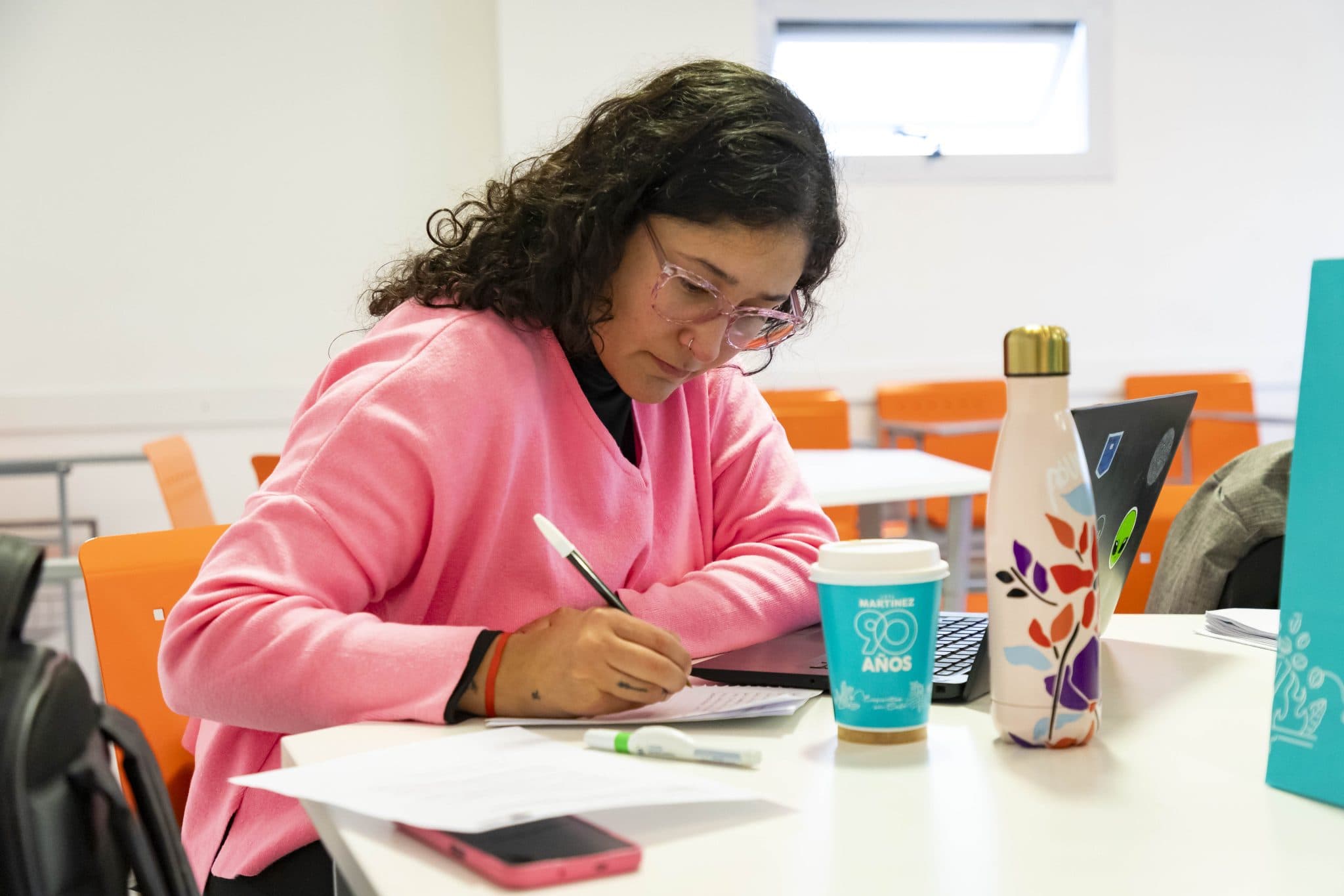 Estudiante tomando apuntes en una mesa de estudio