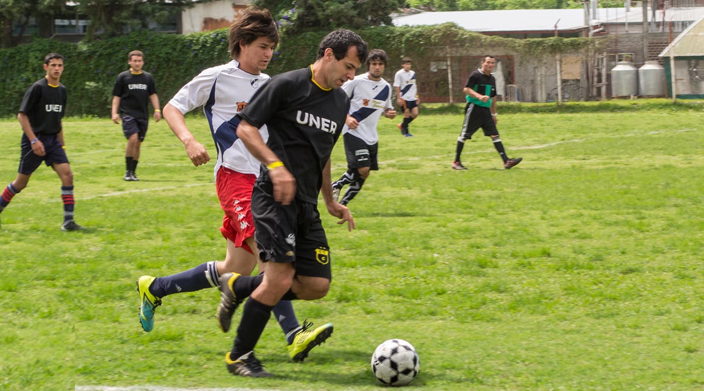 Estudiantes juegan un partido de fútbol en una cancha al aire libre.