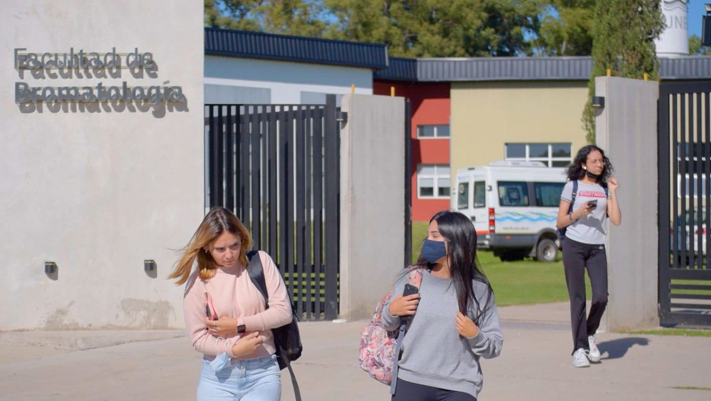 Acceso a la Facultad de Bromatología con estudiantes caminando frente al edificio.