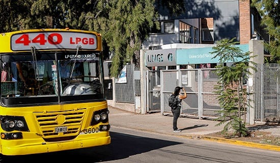 Colectivo urbano frente al acceso de la Universidad Nacional de General Sarmiento, con una persona en la vereda.
