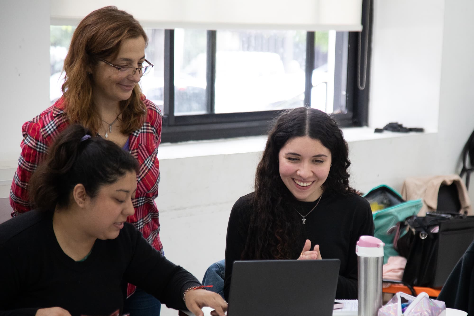 Estudiantes trabajando con una computadora portátil en un aula.