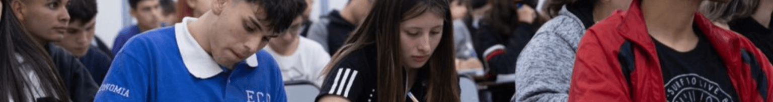Personas sentadas en un aula, concentradas en la lectura y la toma de apuntes.
