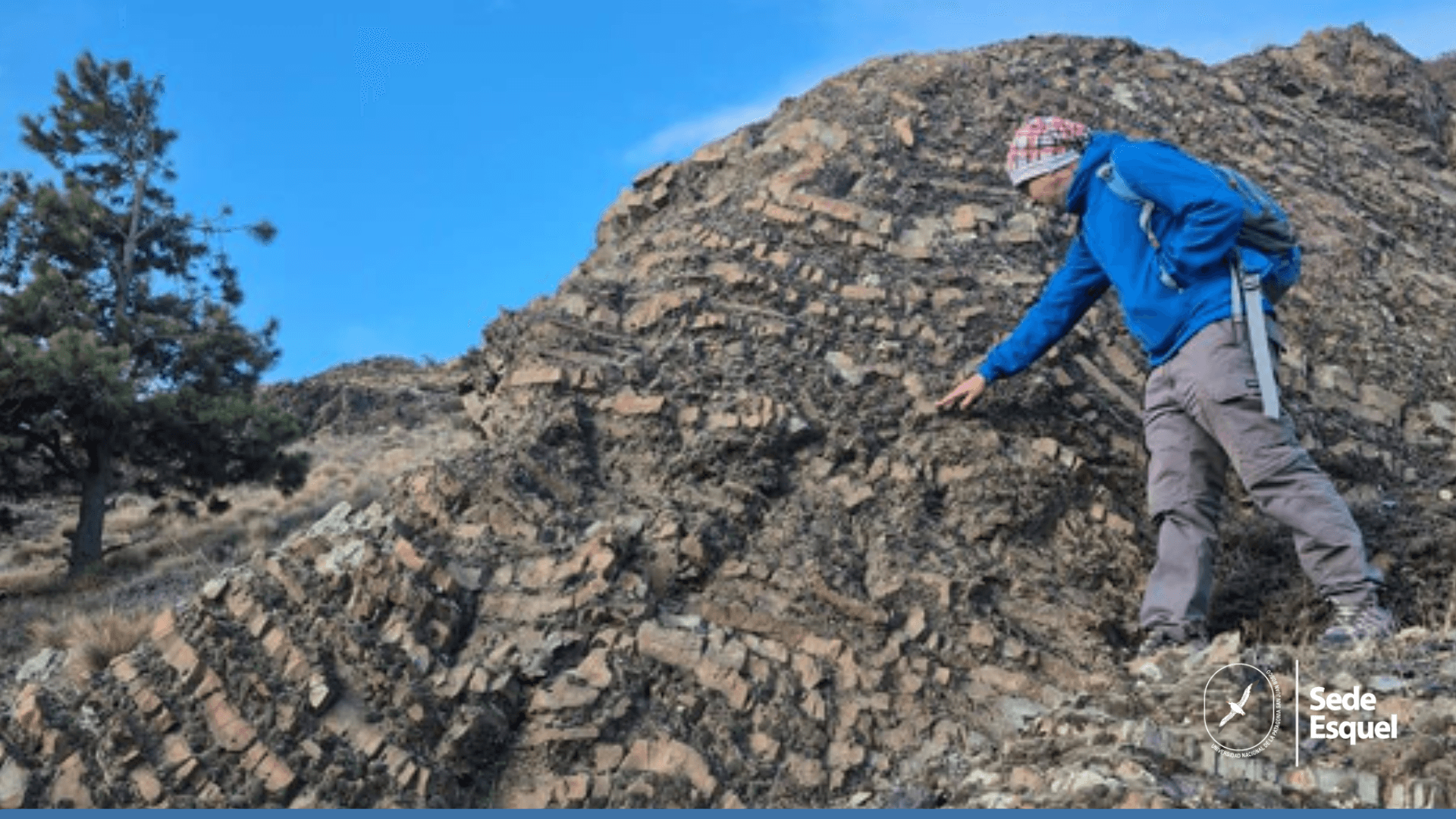 Persona con indumentaria de montaña observa una formación rocosa al aire libre.
