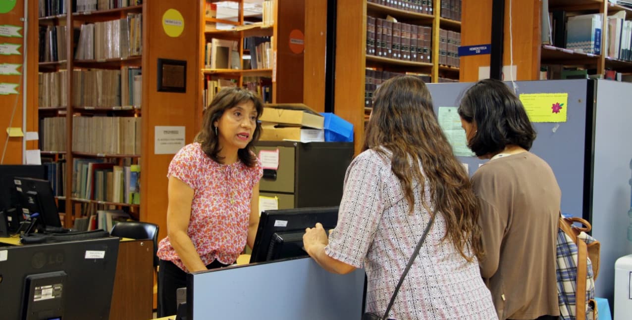 Mostrador de atención y estanterías con libros en la Biblioteca Central I