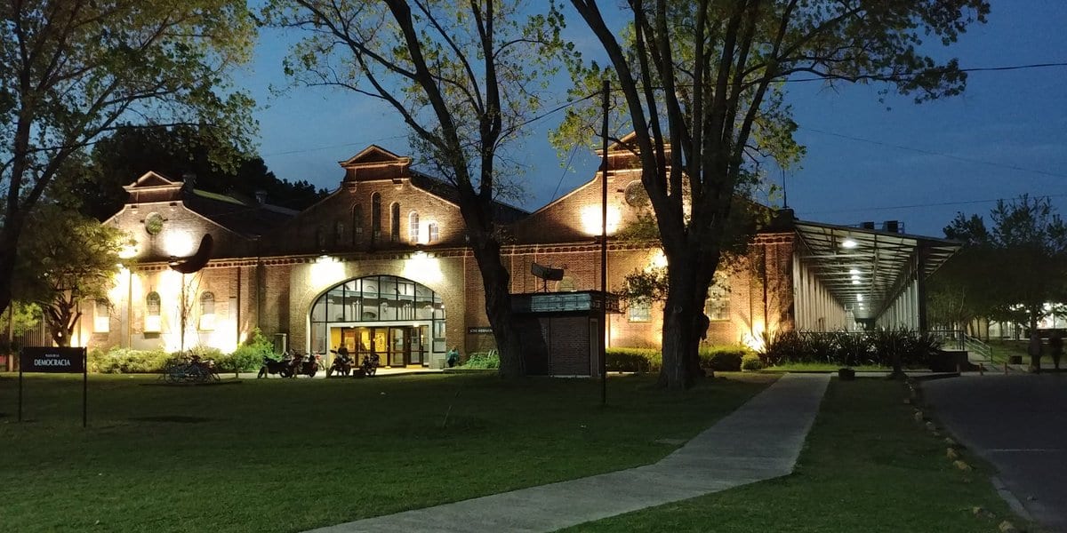 Edificio iluminado y sendero del campus al anochecer