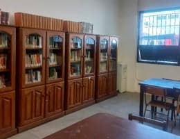Sala con armarios bibliotecarios de madera, una mesa y una ventana.