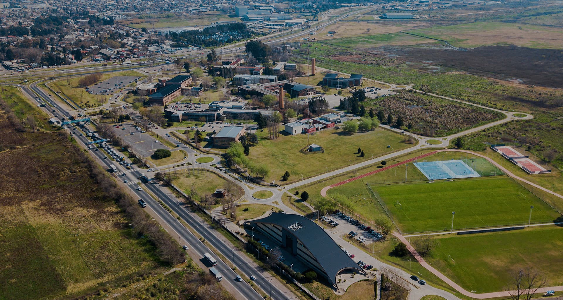 Vista aérea del campus de la Universidad Nacional de Lomas de Zamora, con edificios, espacios verdes y canchas.