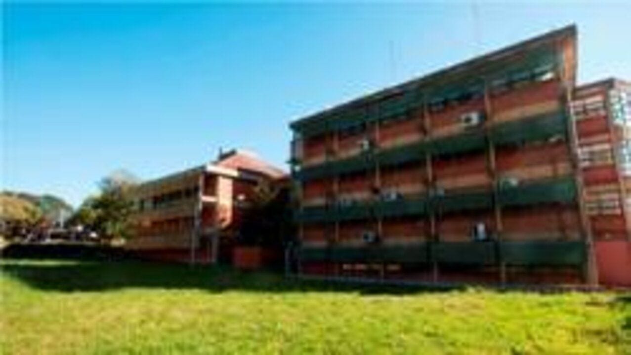 Edificio de varios niveles rodeado de césped en un espacio universitario.