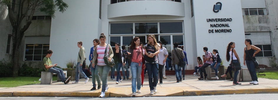 Estudiantes frente al acceso de un edificio con el nombre Universidad Nacional de Moreno.