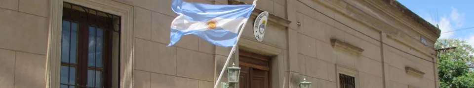 Fachada de un edificio universitario de la UNSAdA con una bandera argentina en el acceso.