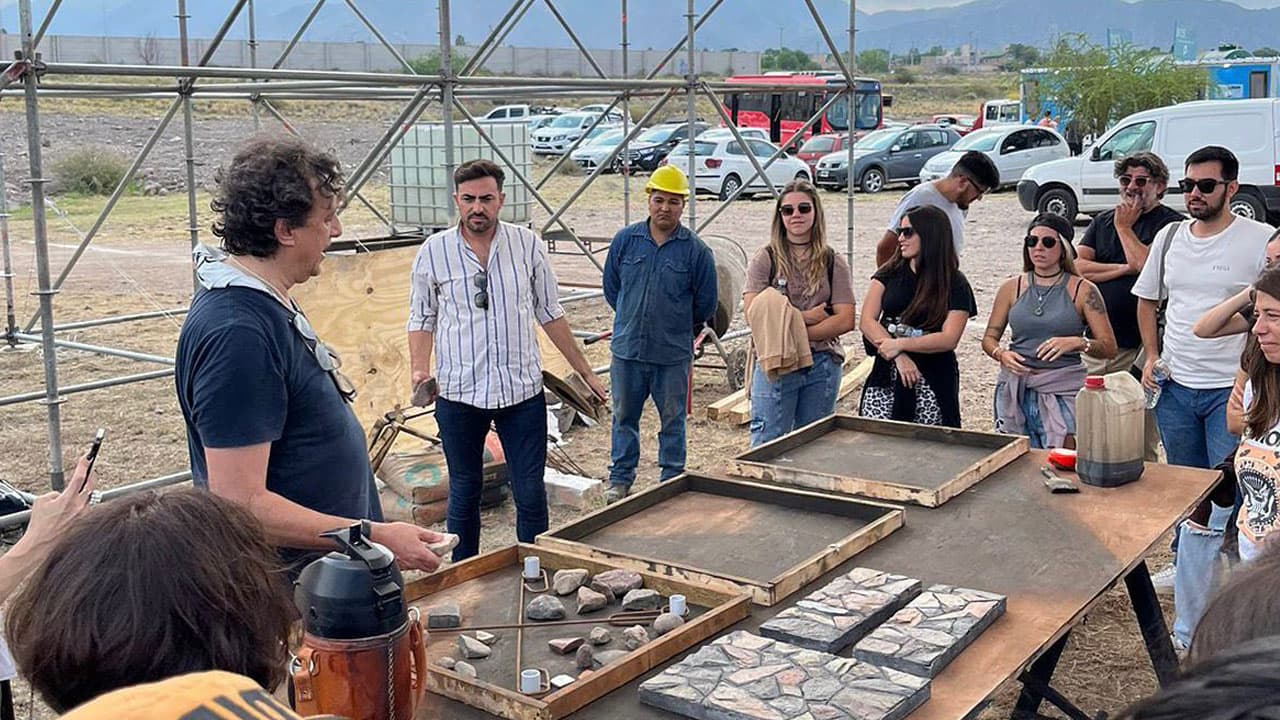 Grupo de estudiantes y docentes observa materiales sobre una mesa durante una actividad al aire libre