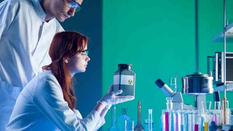 Dos personas con guardapolvo trabajan con material de laboratorio