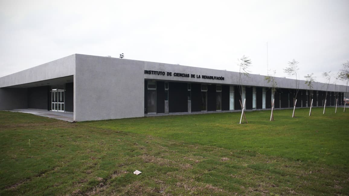 Edificio bajo de hormigón con el letrero del Instituto de Ciencias de la Rehabilitación, rodeado de césped.