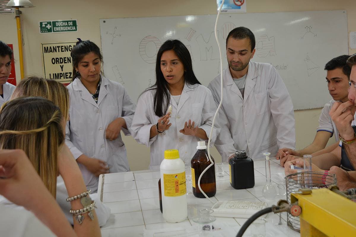Grupo de estudiantes con guardapolvos durante una práctica en laboratorio.