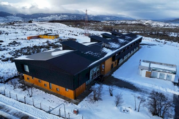 Vista aérea de un edificio del campus de la Universidad Nacional de Tierra del Fuego rodeado de nieve.