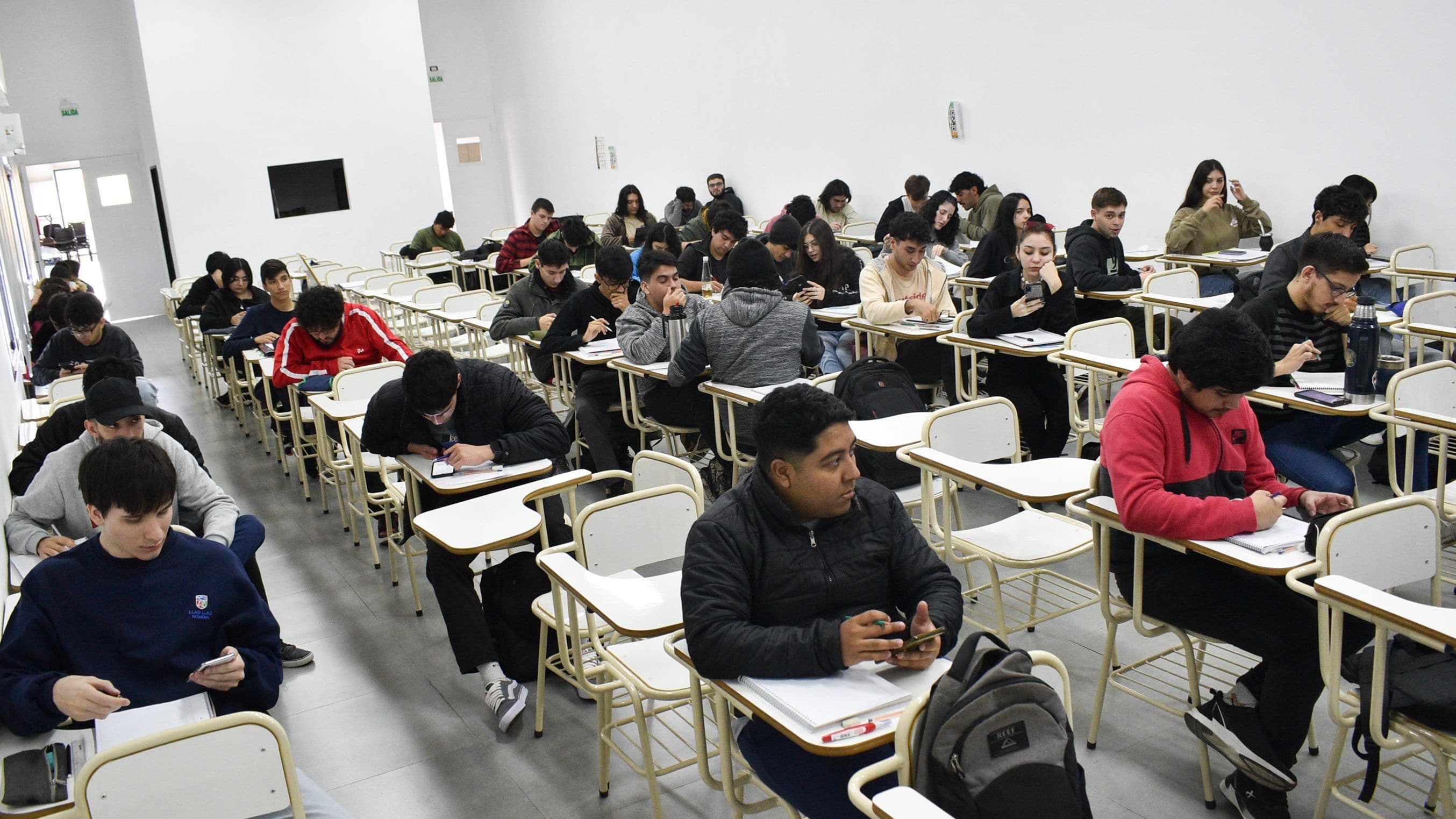 Estudiantes sentados en un aula mientras realizan una actividad con sus teléfonos