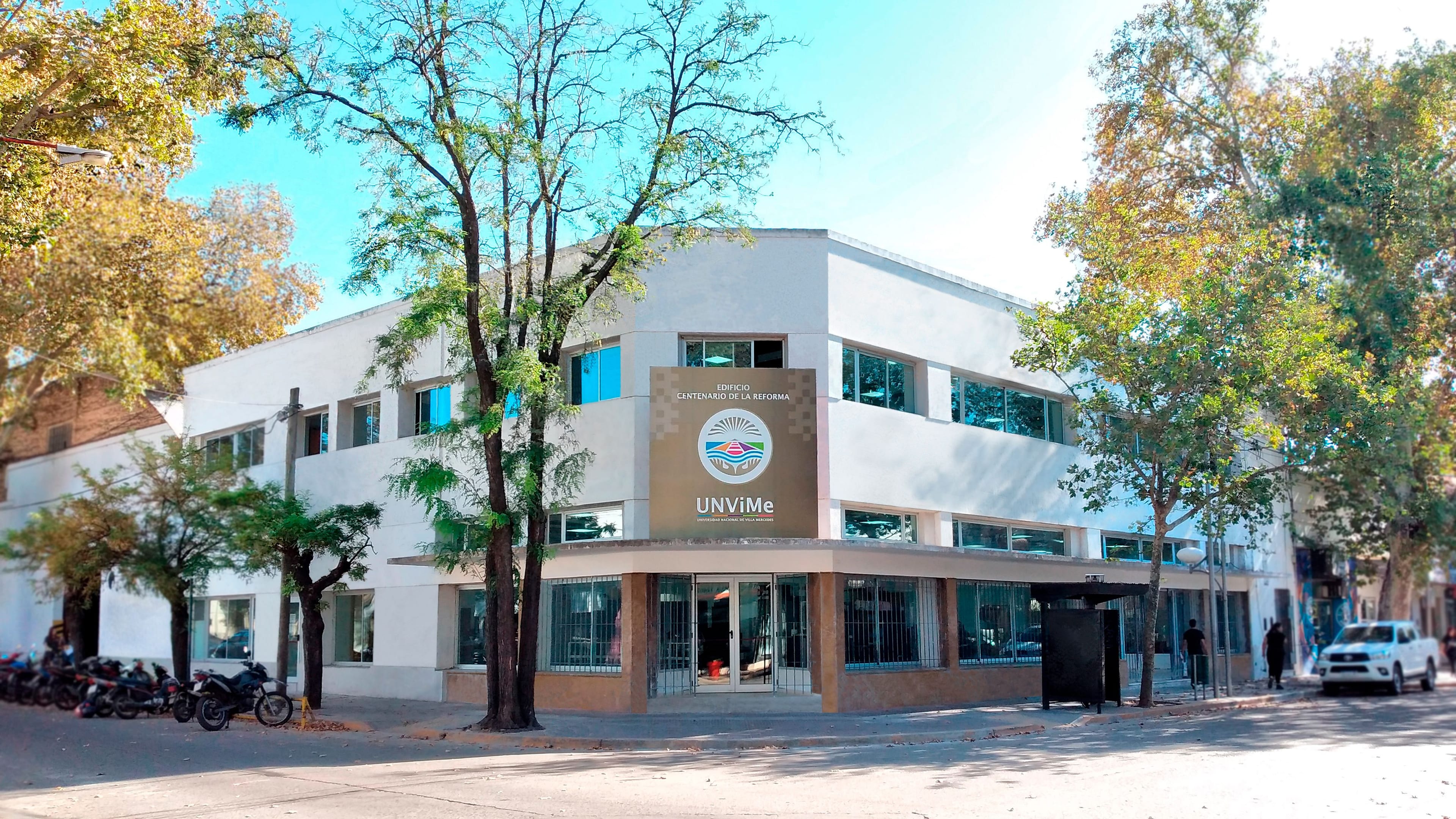 Fachada de un edificio de la UNViMe con arbolado sobre la vereda