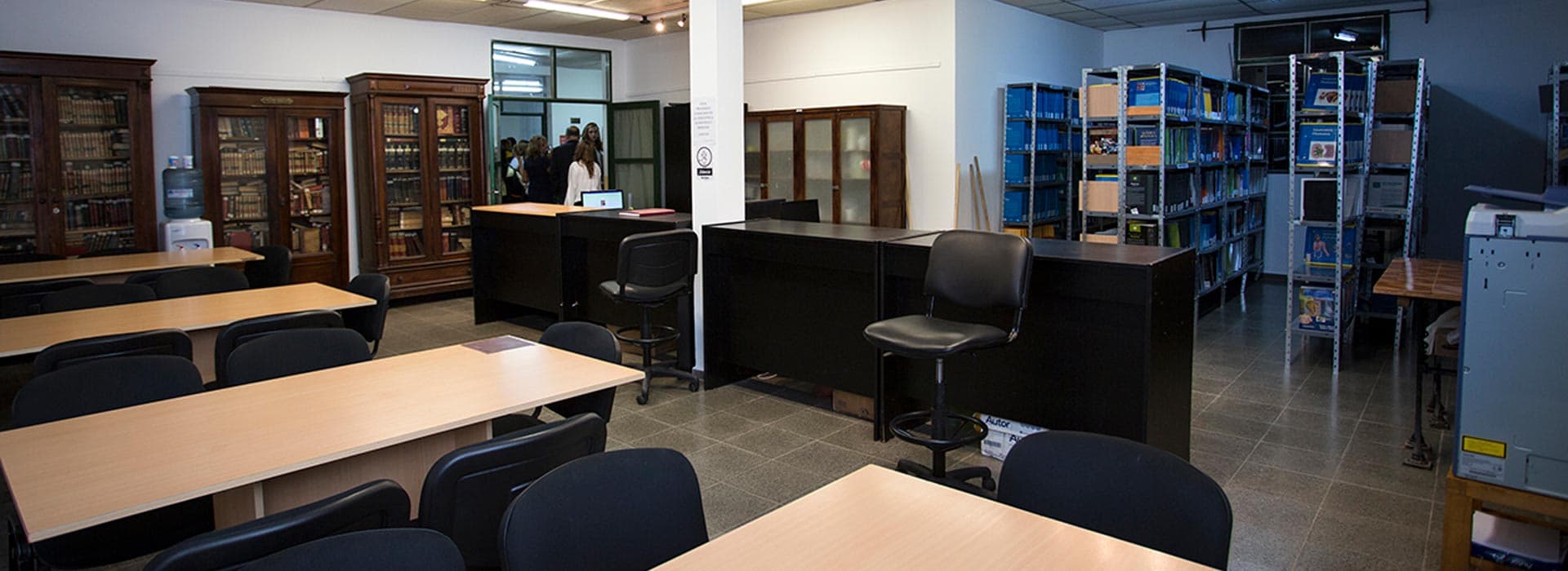 Sala de biblioteca con mesas, sillas, mostradores y estanterías de libros