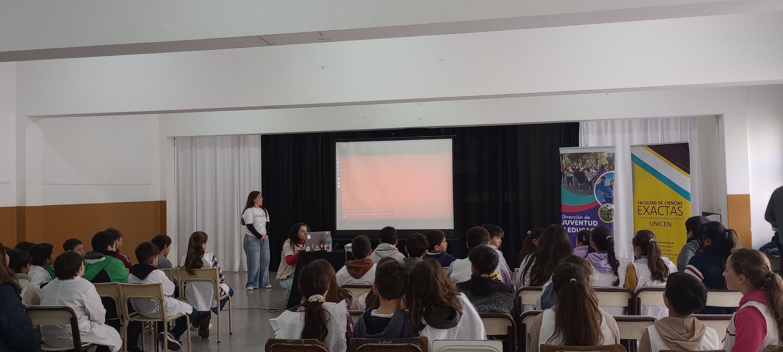Personas asistentes a una actividad con proyección en un salón universitario