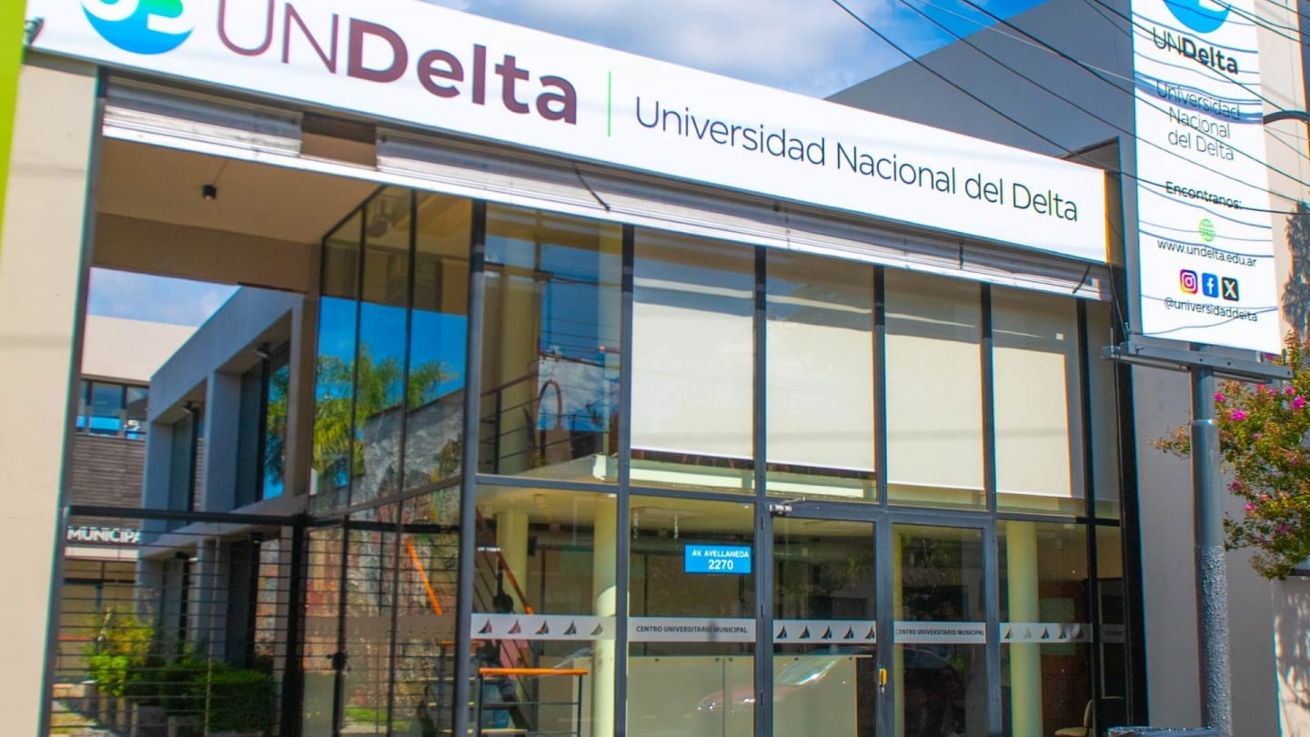 Fachada vidriada de la Universidad Nacional del Delta con el nombre institucional sobre el acceso.