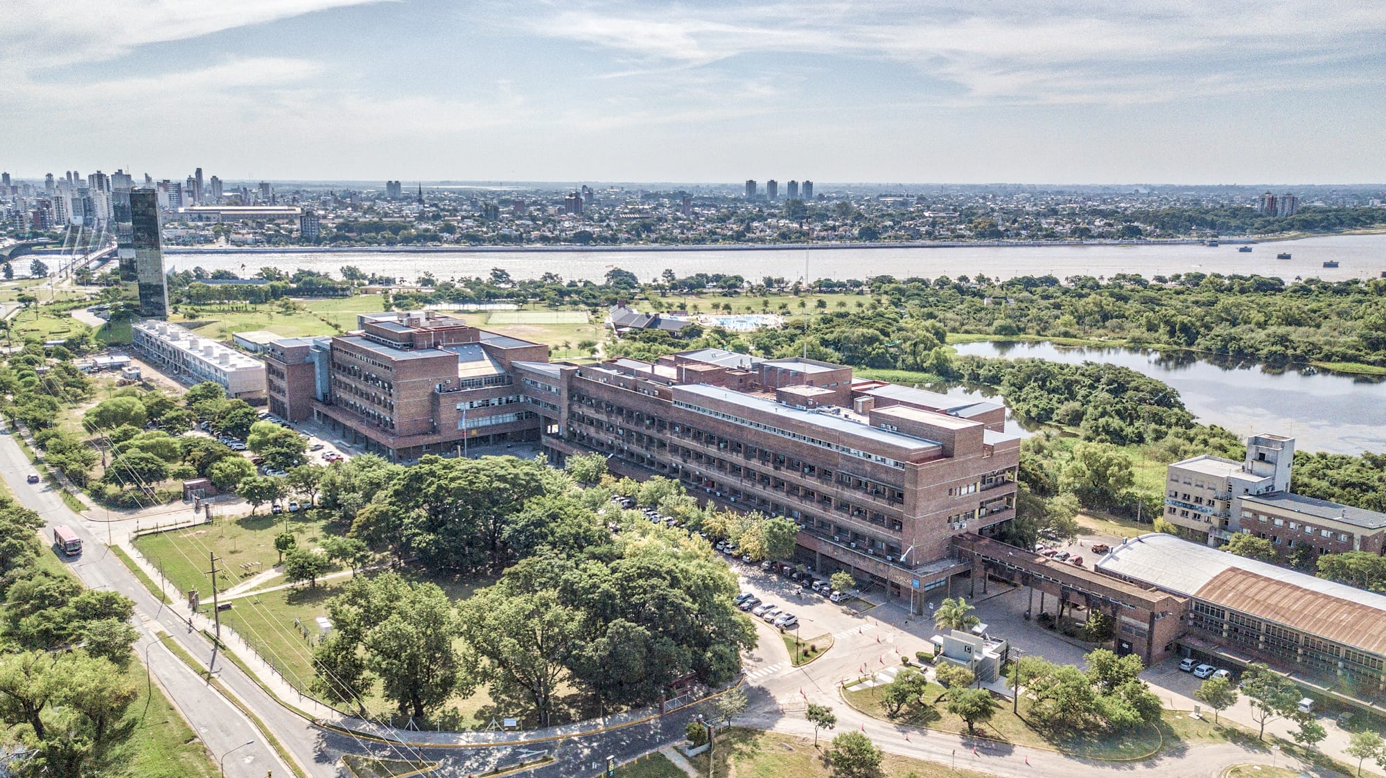 Vista aérea de un conjunto de edificios universitarios rodeados de arbolado y avenidas, junto al río.