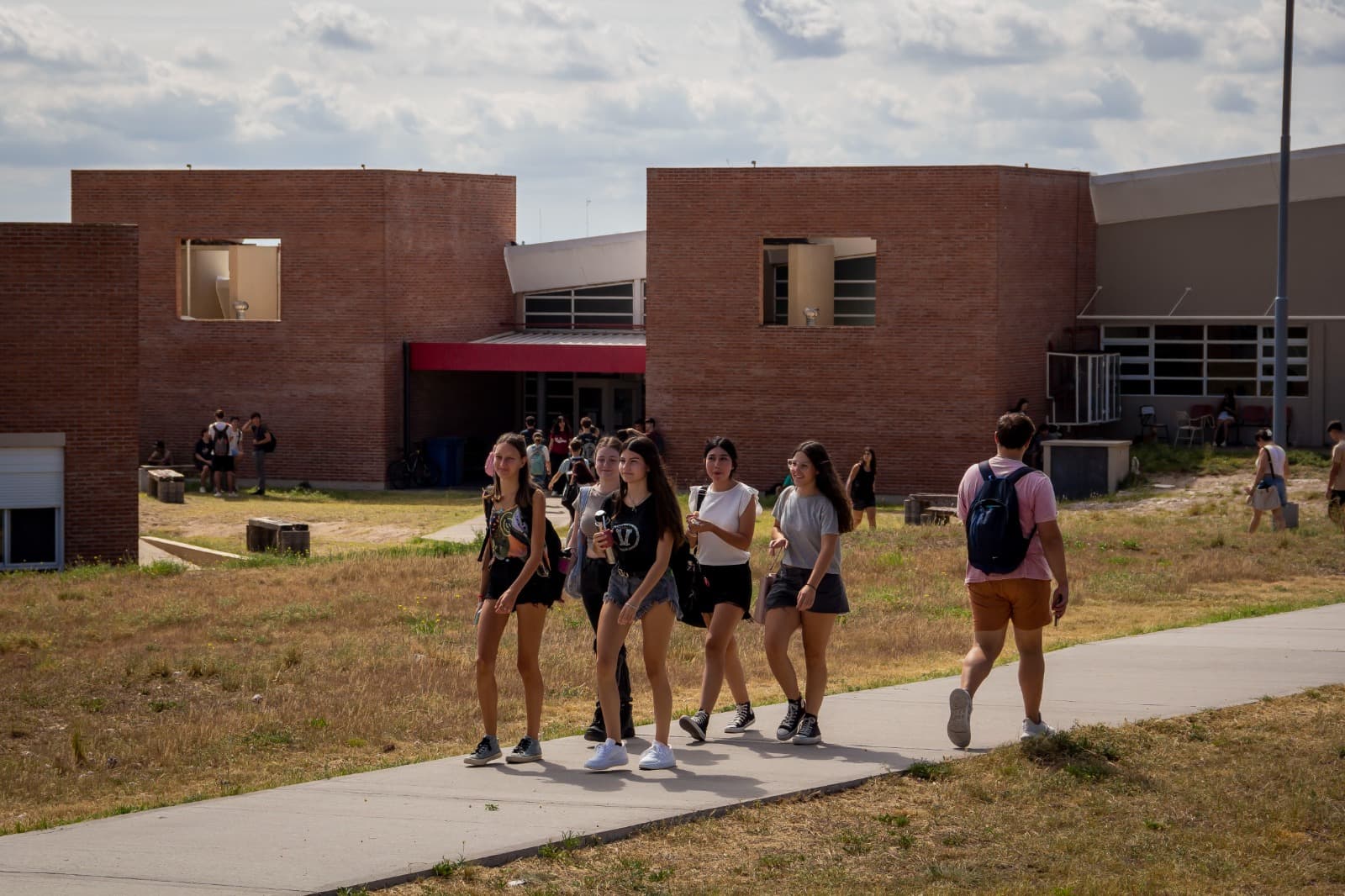 Grupo de estudiantes camina por un sendero junto a un edificio universitario.