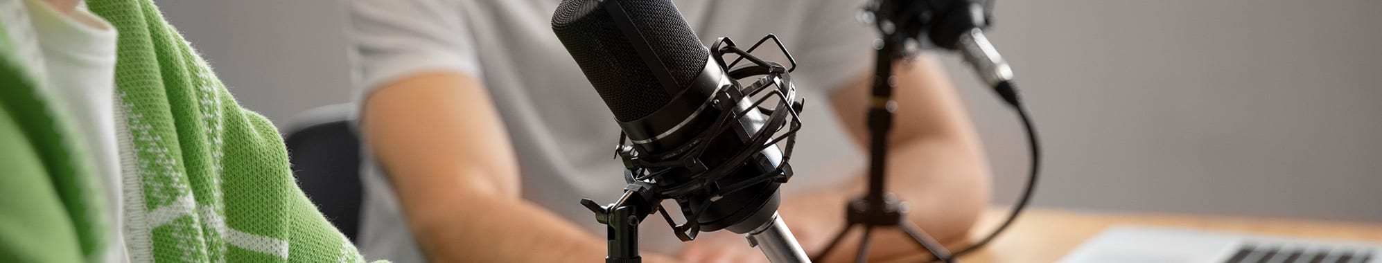 Micrófono de estudio frente a una persona sentada con auriculares