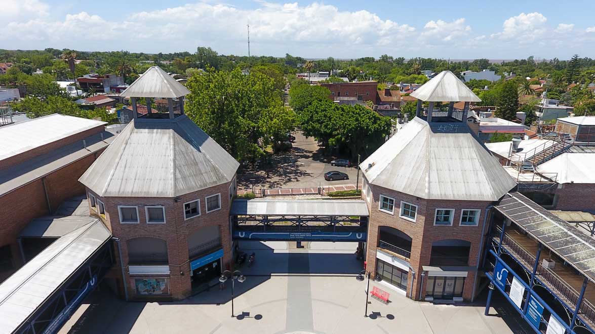 Vista aérea de dos edificios de ladrillo con cubiertas piramidales y un patio arbolado detrás.