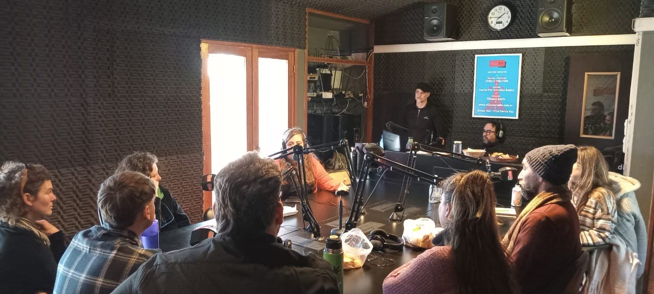 Grupo de personas participa de una actividad con micrófonos y equipos de audio en un estudio.
